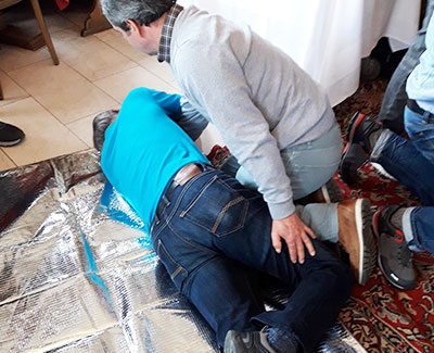 Teilnehmer eines Erste-Hilfe-Kurses bringen eine Person in die stabile Seitenlage. Professionelle Erste-Hilfe-Schulung für Unternehmen und Privatpersonen.